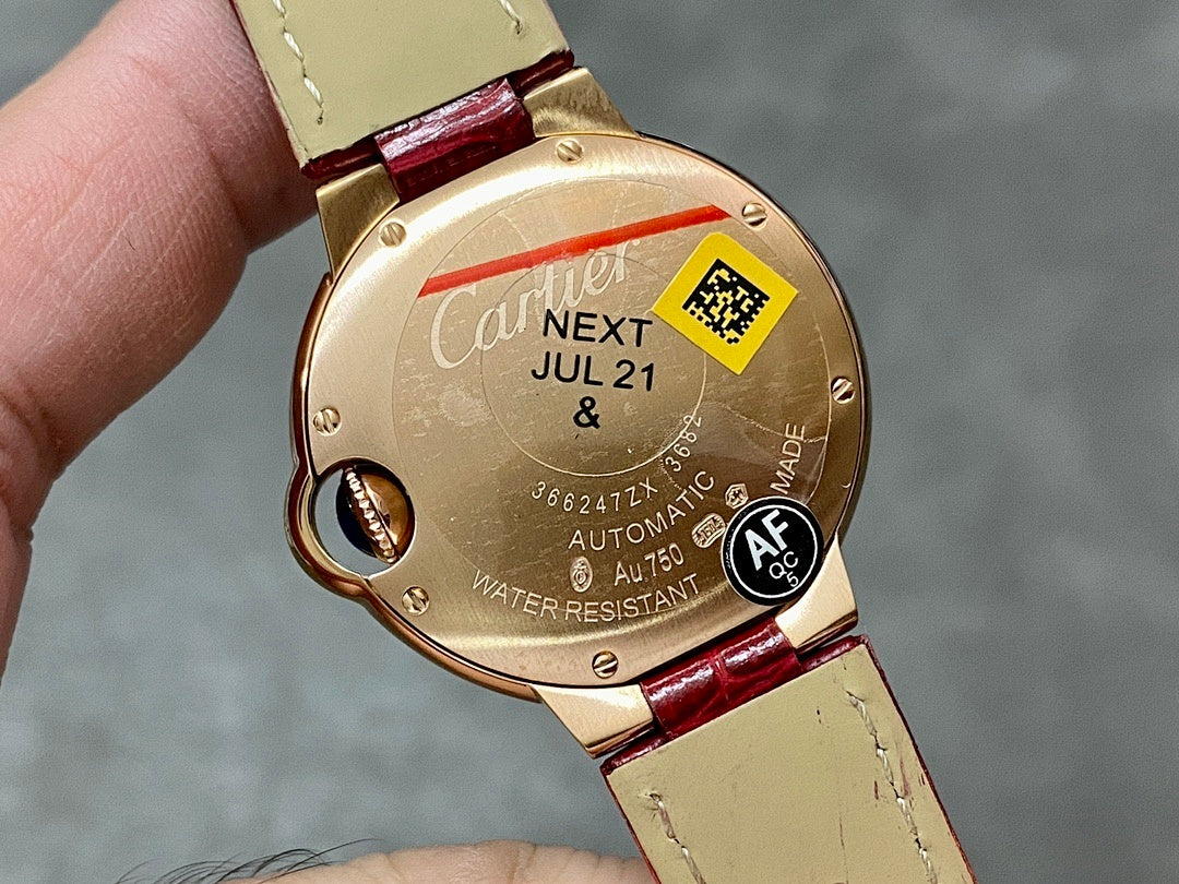 Back of round wristwatch with gold-tone case, red strap, date text and water-resistant marking