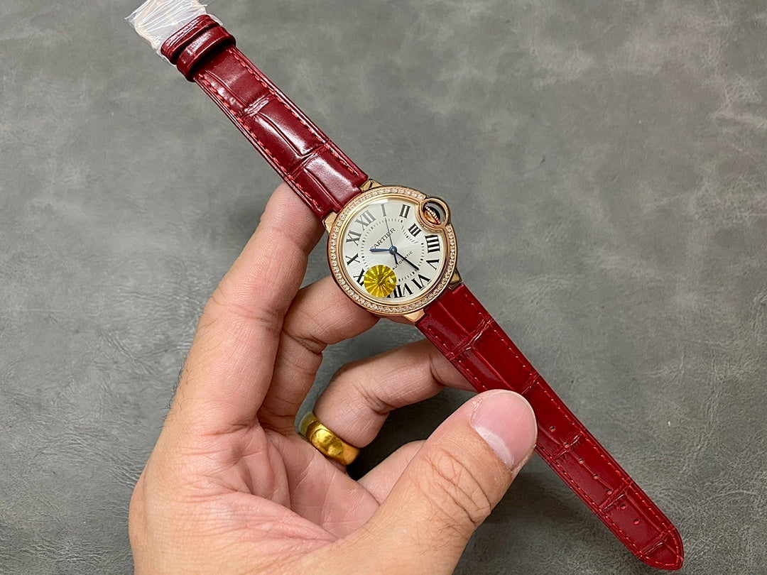 Cartier wristwatch held in hand: red leather strap, gold-tone case, Roman numeral dial