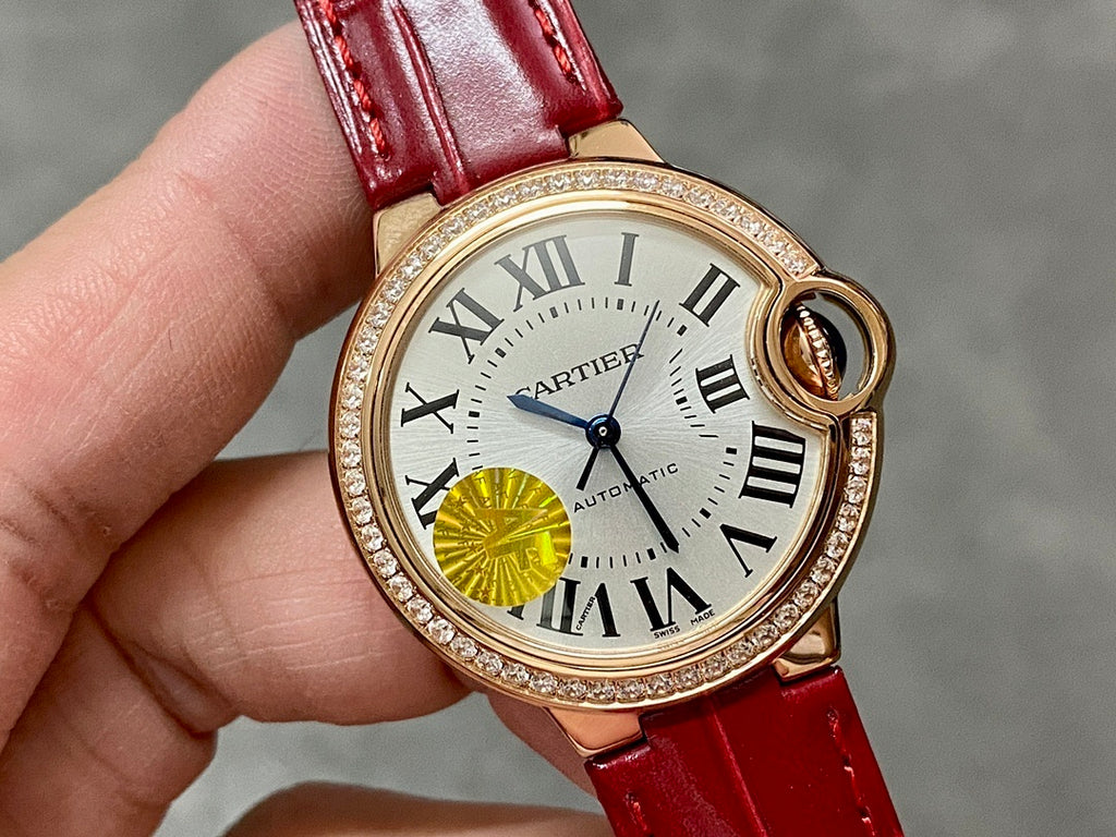 Round wristwatch close-up: red leather strap, gold-tone bezel with Roman numerals and yellow detail