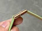 Gold-tone watch crown and case side on green leather strap