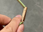 Gold-tone watch side profile on green leather strap