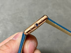 Gold-tone watch case with blue leather strap and blue gemstone crown