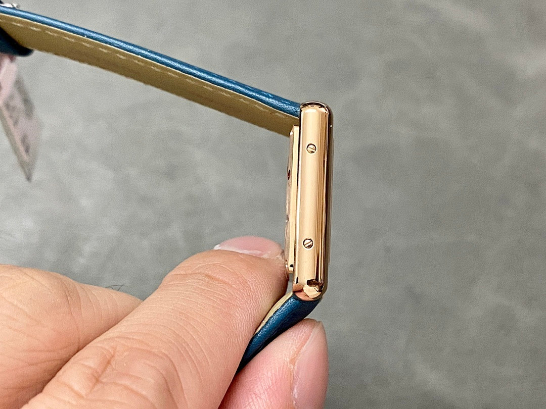 Gold-tone watch case side with screw details and blue leather strap