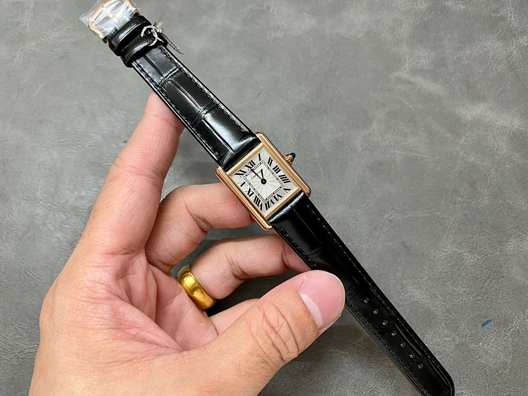 Cartier watch held in hand: black leather strap, gold case, white dial with Roman numerals