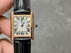 Cartier watch front close-up: black leather strap, gold-toned case, white dial, Roman numerals