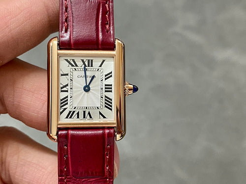 Cartier tank watch front view with burgundy strap, gold case, Roman numeral dial