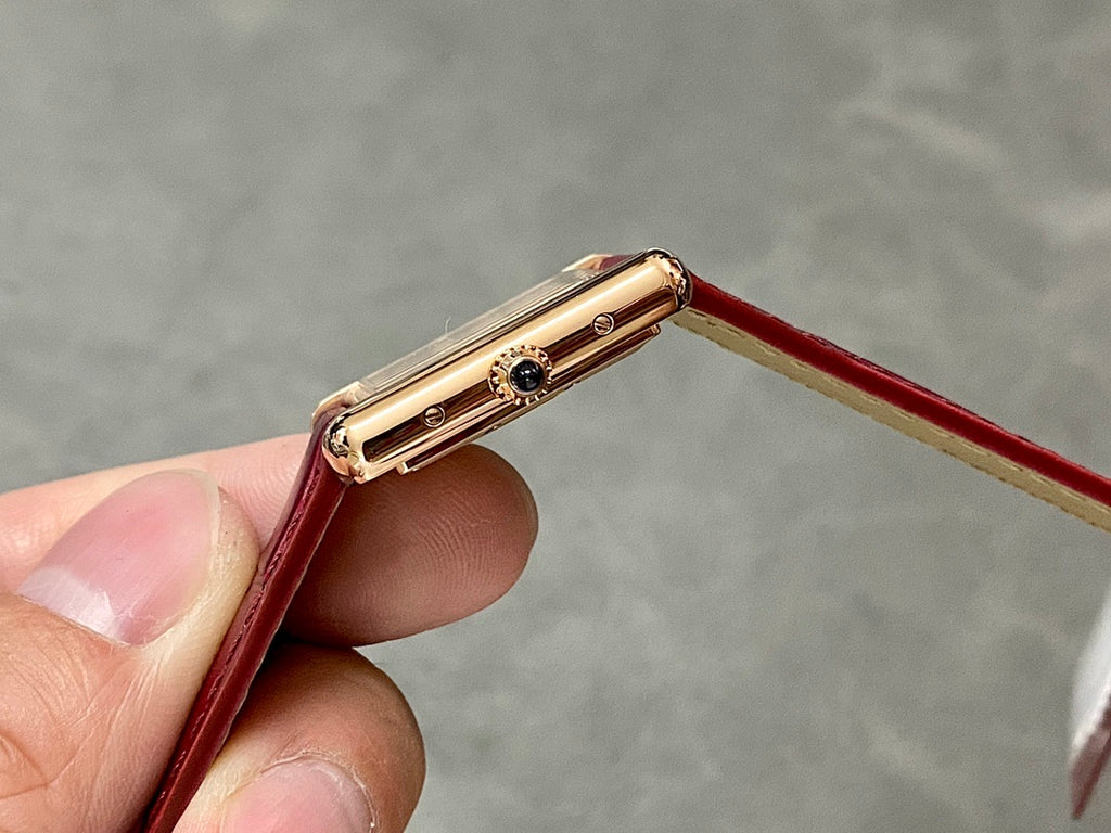 Gold-tone watch case side with crown and pushers, burgundy leather band