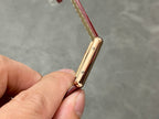 Gold-tone watch case side profile with crown, burgundy leather strap