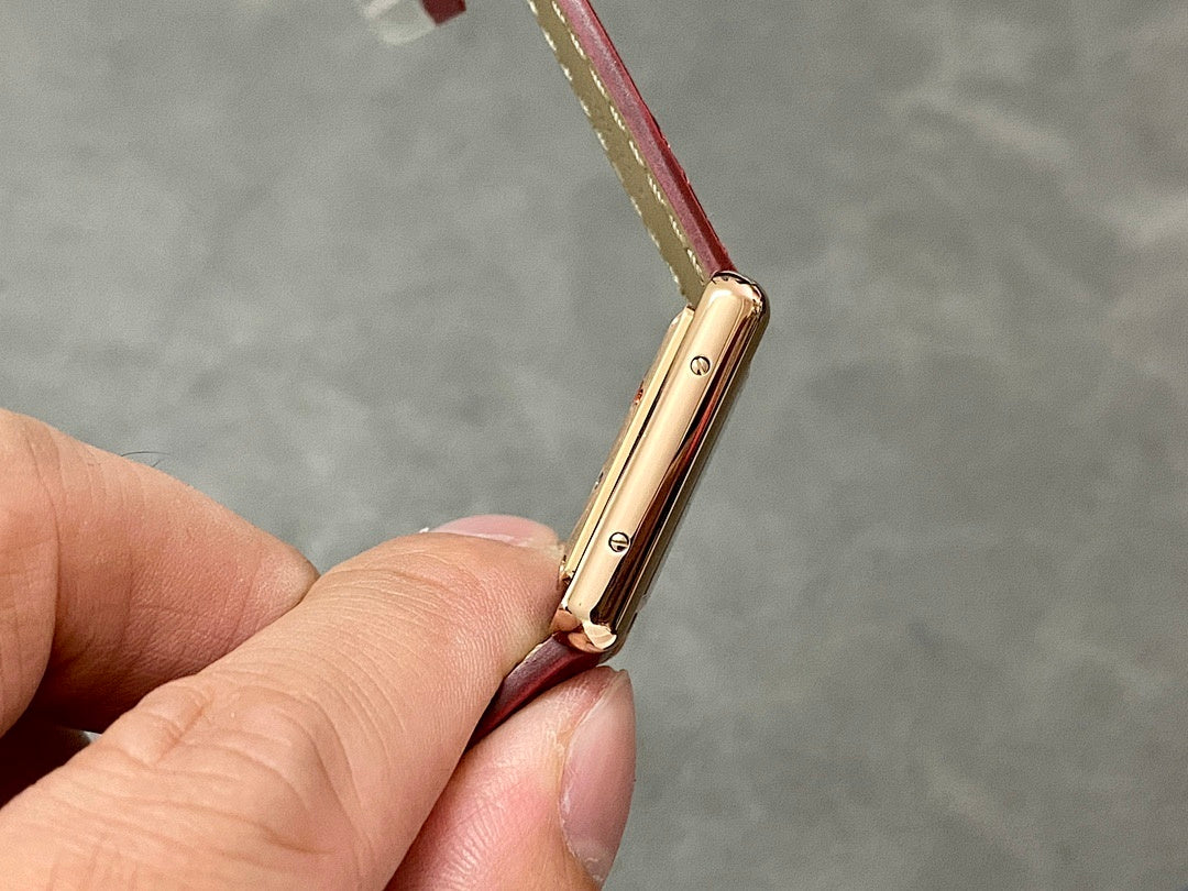 Gold-tone watch case side profile with crown, burgundy leather strap