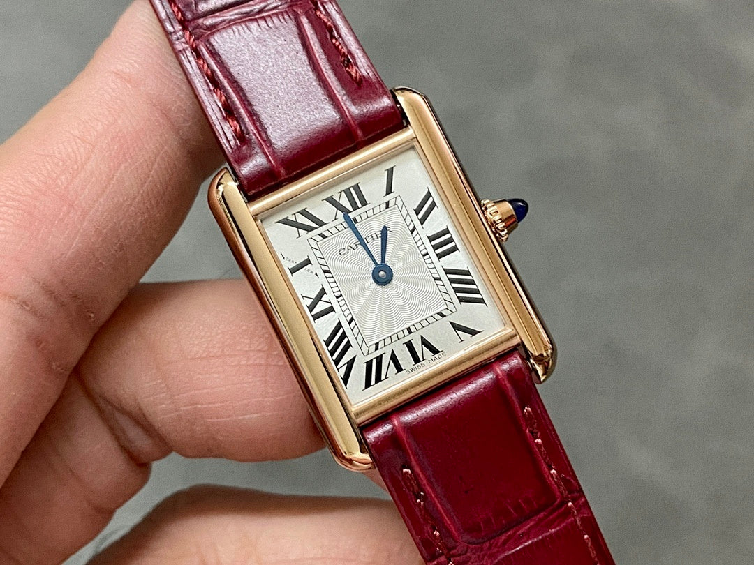 Cartier tank watch close-up with burgundy leather strap and gold-tone Roman dial