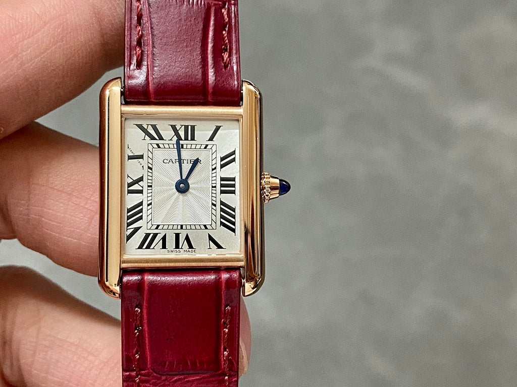 Cartier tank watch front with burgundy strap and gold-tone rectangular case