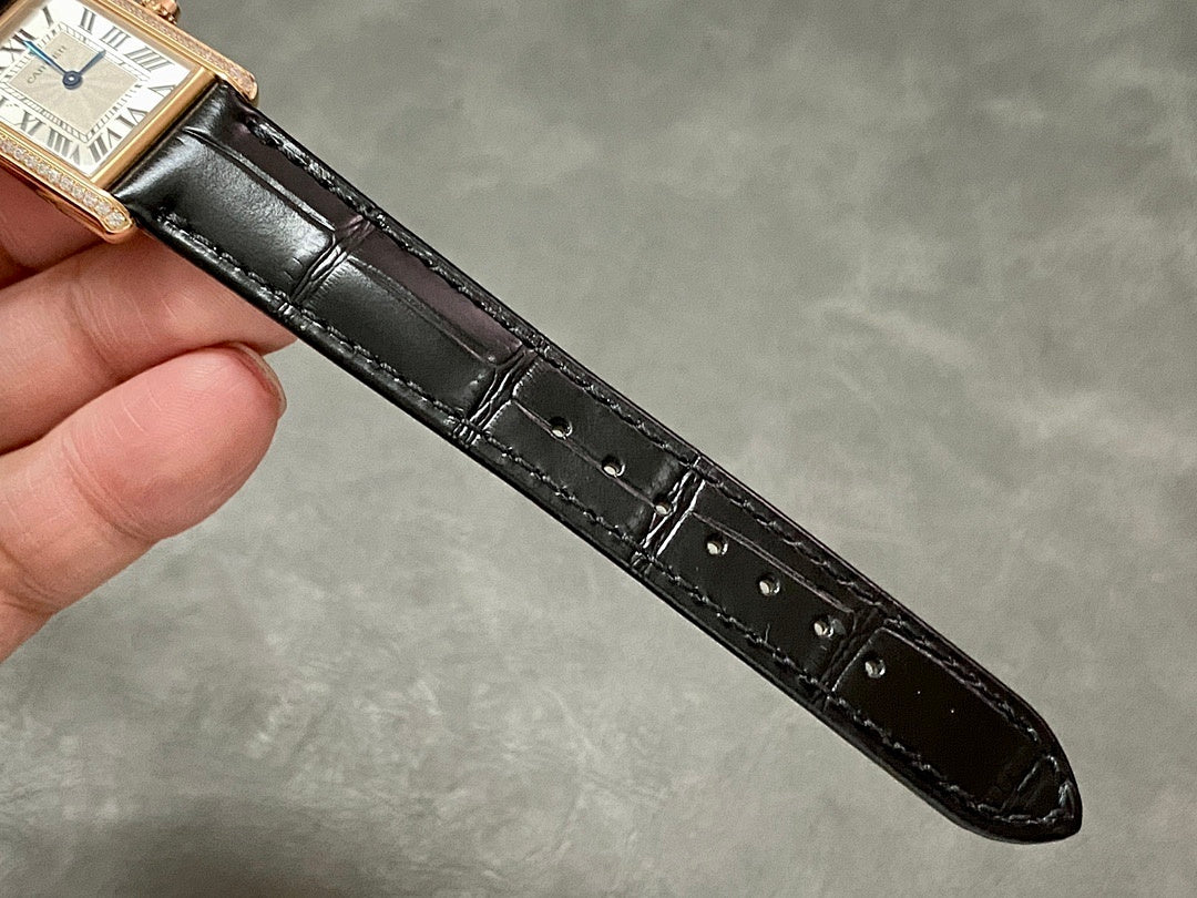 Black leather watch strap with stitched edge and buckle holes, attached to rose-gold case.