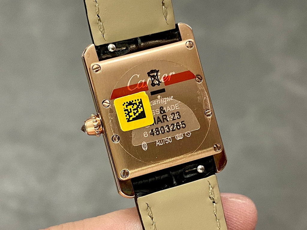 Cartier watch case back in rose-gold with stamped markings and serial text, on black strap.