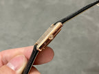Rose-gold watch case side with crown and bezel, black leather strap visible.