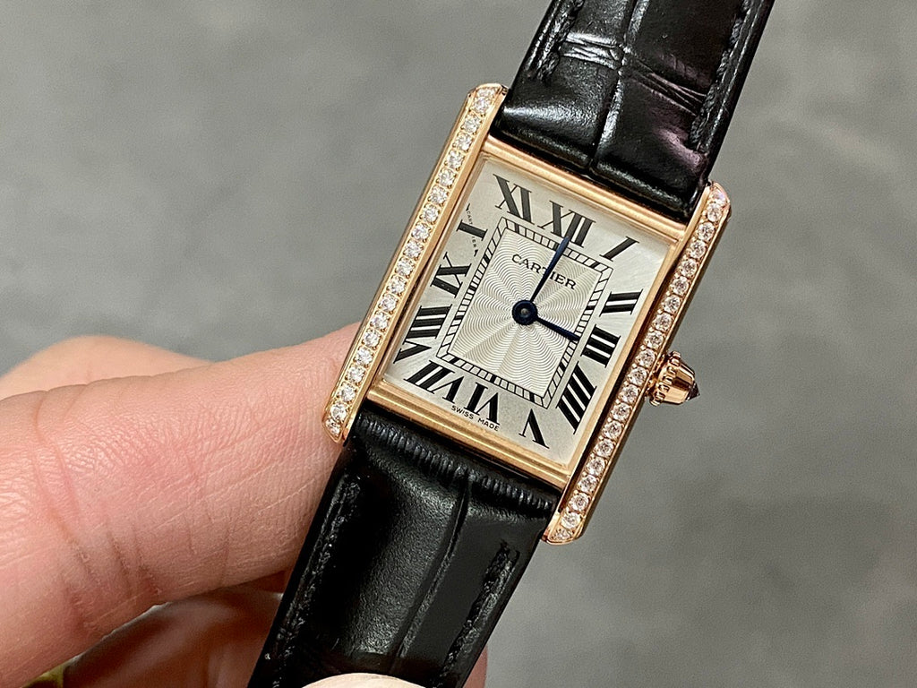 Cartier rose-gold wristwatch with black leather strap, diamond bezel, Roman numeral dial.