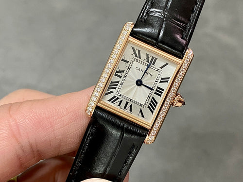 Cartier rose-gold wristwatch with black leather strap, diamond bezel, Roman numeral dial.