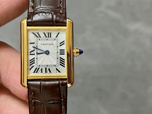 Cartier watch with gold rectangular case, white dial, Roman numerals, brown leather strap