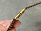 Cartier watch side view with gold crown and blue gem, brown leather strap