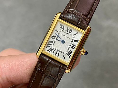 Cartier watch with gold case, white dial, Roman numerals, brown leather strap