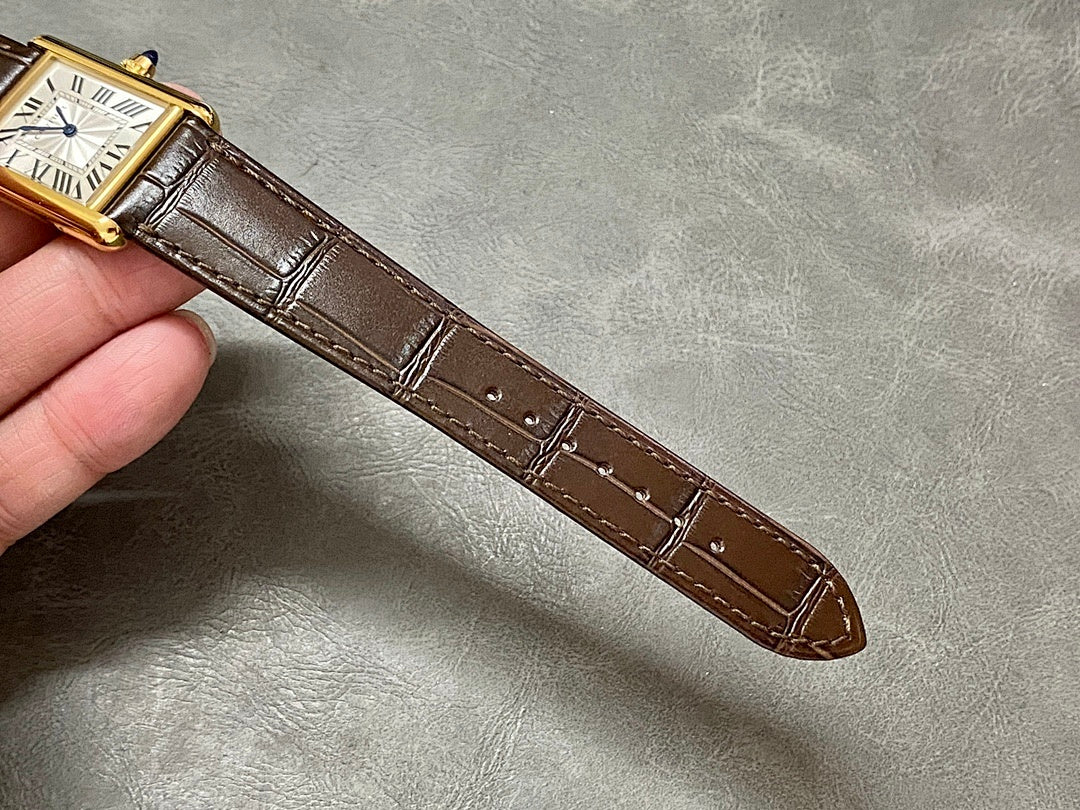 Brown leather watch strap with rectangular gold-tone case shown from the side