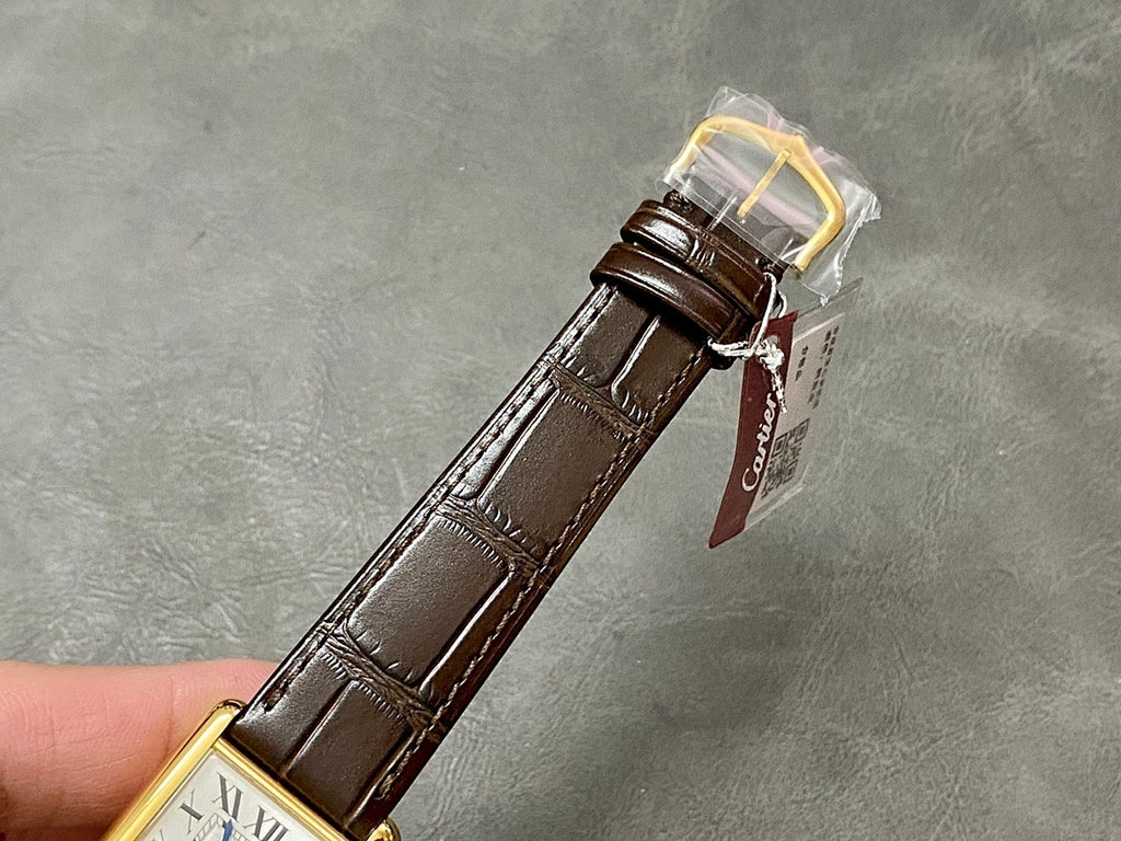 Rectangular wristwatch with brown leather strap and gold-tone case, tag attached at buckle