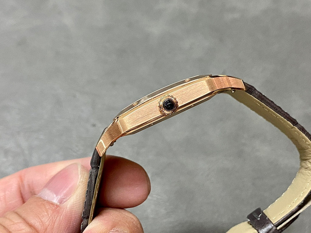 Cartier Santos watch side profile with rose-gold case and black leather strap.