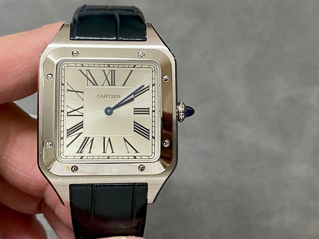 Cartier rectangular watch on hand; black leather strap, Roman dial, silver case, crown.