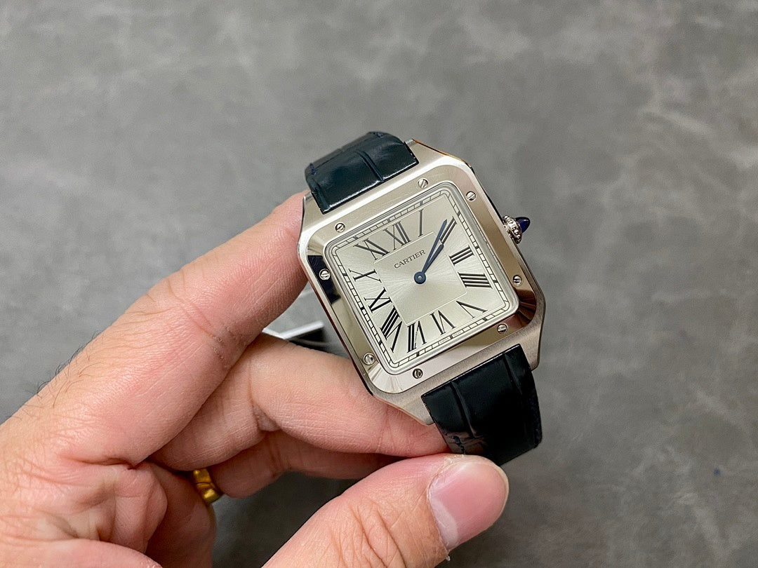 Cartier rectangular watch held in hand; black leather strap, Roman numeral dial, silver case.