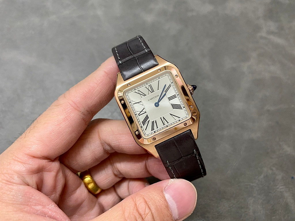 Cartier watch on hand with gold-tone square case, white dial, Roman numerals, black leather strap