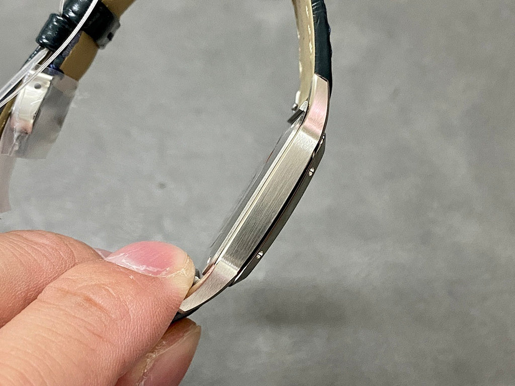 Cartier watch curved side view with dark leather strap and silver-toned case.