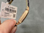Wristwatch with black leather strap and tag showing barcode, gold-tone case.