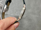 Cartier wristwatch side view with black leather strap and polished metal bezel