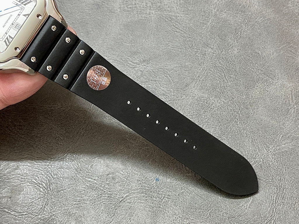 Black leather watch strap with stud details and engraved circular stamp near buckle end
