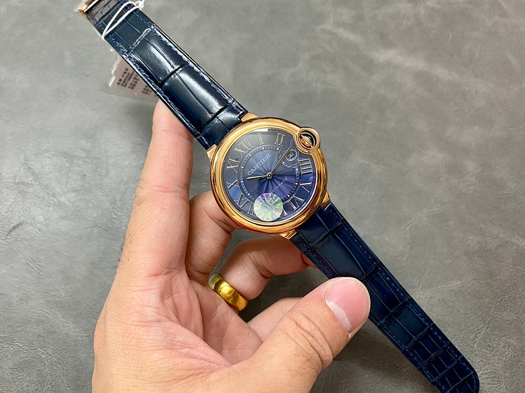 Cartier watch held in hand: gold case, blue dial, and blue leather strap