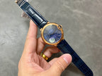 Cartier watch held in hand: gold case, blue dial, and blue leather strap