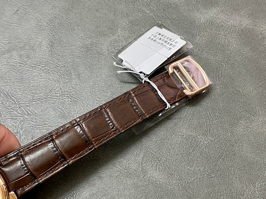 Brown leather watch strap with rose-gold clasp and attached paper tag