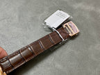 Brown leather watch strap with rose-gold clasp and attached paper tag