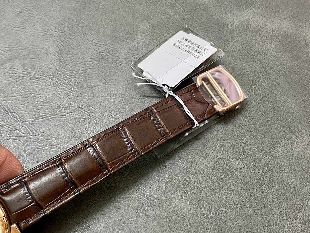 Brown leather watch strap with rose-gold clasp and attached paper tag