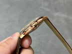 Rose-gold watch case side profile with crown, on brown leather strap