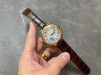 Cartier watch held in hand with brown leather strap, rose-gold case, white dial