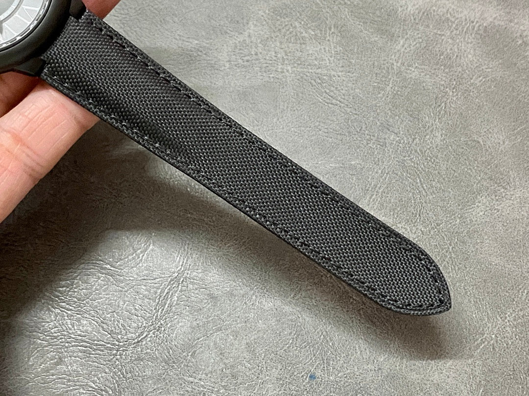 Black fabric watch strap with textured weave, laid flat