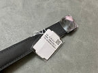 Black fabric watch strap with metal buckle and white barcode tag