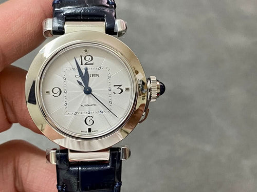 Cartier wristwatch front view with silver dial, blue leather strap, and crown details.