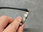 Cartier wristwatch side profile showing silver case and dark blue strap attachment.