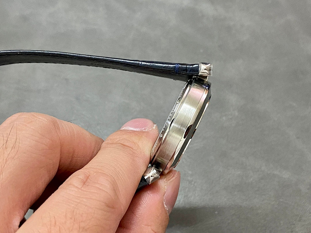 Cartier wristwatch side profile showing silver case and dark blue strap attachment.