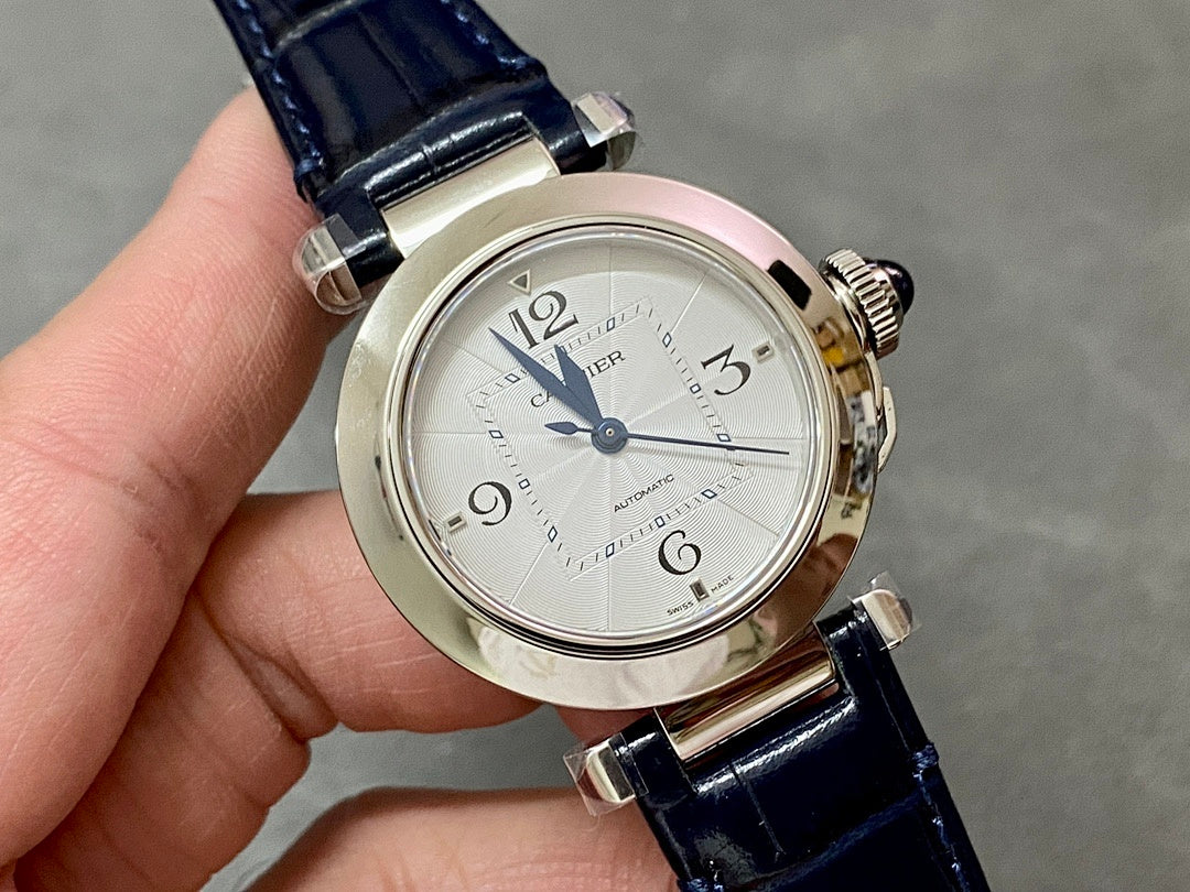 Cartier wristwatch angled view with silver dial, dark blue leather strap, and metal case.