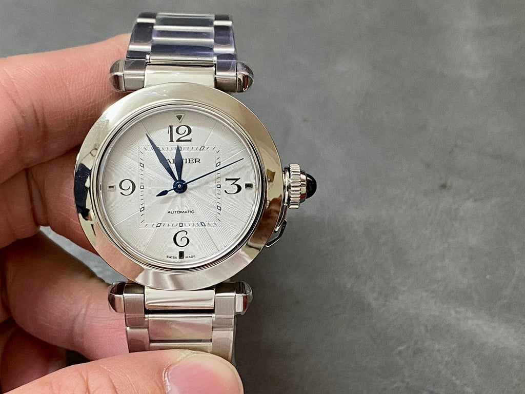 Cartier watch with silver metal bracelet and white dial, blue hands, visible crown on case