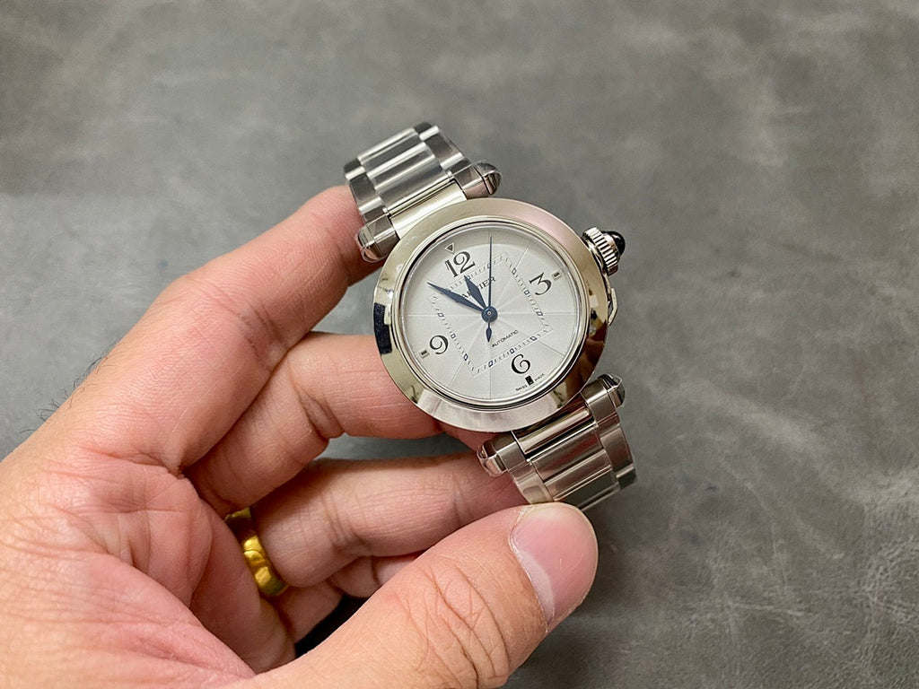 Cartier watch with silver metal bracelet and white dial, blue hands, crown detail
