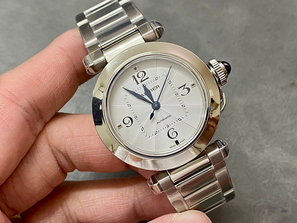 Cartier watch with silver metal bracelet, white dial, blue hands and raised bezel
