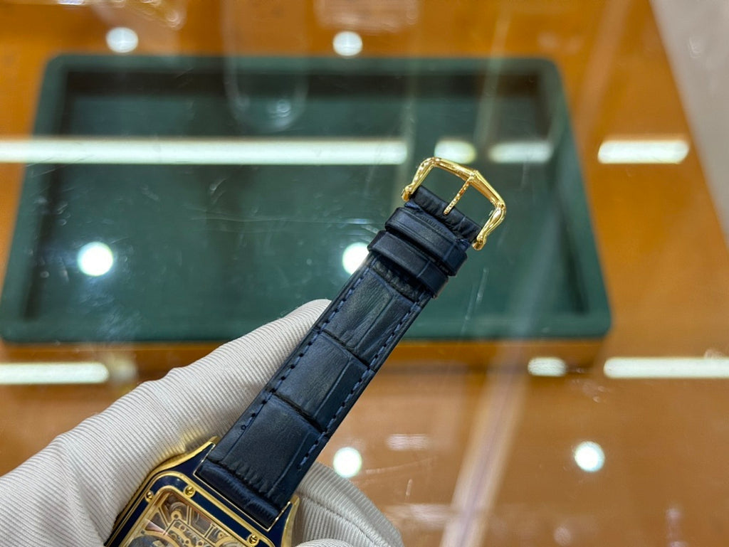Gold-tone wristwatch with black leather strap and buckle, shown from side